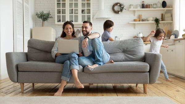 Jundes Paar mit Laptop auf einem grauen Sofa